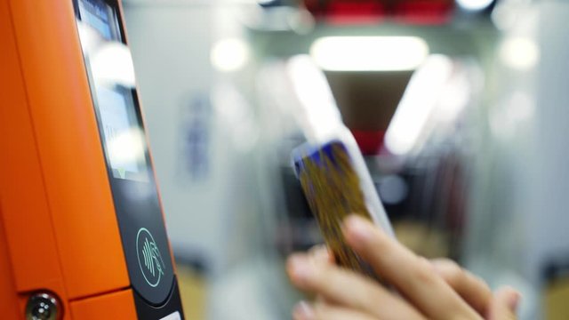 Faceless passenger paying via electronic device in public transport. Detail view female choosing trip options on modern tram validator making contactless payments via smartphone at blurred background