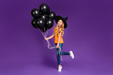Full size photo of little witch lady halloween party holding many air balloons excited chilling wear orange t-shirt wizard hat isolated purple color background
