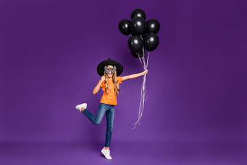 Full size photo of little lady october party hold air balloons came children theme party hide face bat mask wear orange t-shirt witch hat isolated purple color background