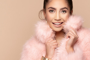 Fashionable smiling girl in pink eco fur.