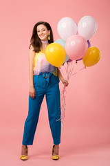 young happy party girl holding festive balloons on pink