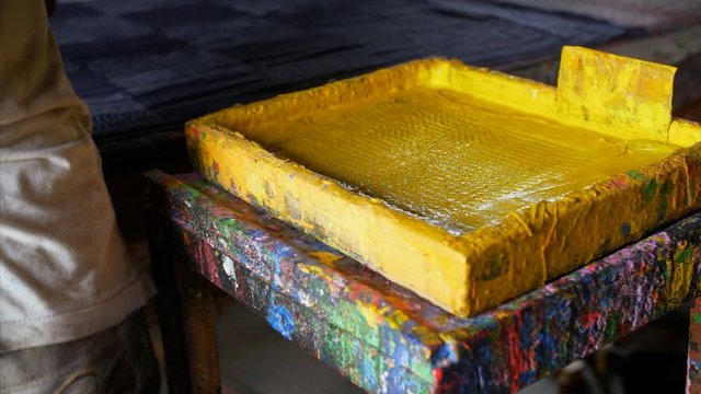 Block Printing - A worker dips the block into the trays of yellow colored dye. 