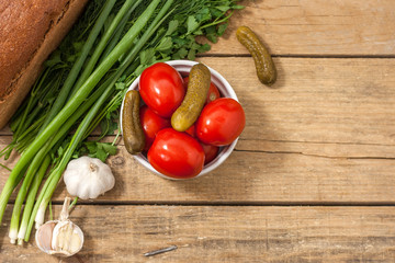 Fermented food on a white plate on an old wooden table. Pickled tomatoes and cucumbers. Salt for the winter. Traditional snack for alcohol.