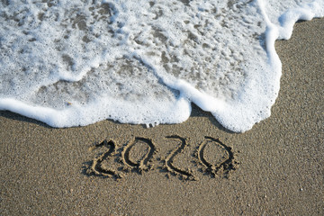 New year 2020 on sandy beach with waves.