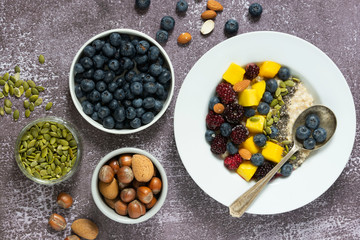 Healthy breakfast with oatmeal porridge, fruits and nuts. Blueberry, mango, pumpkin seeds, nuts, coffee cup. Top view. Clean eating, dieting, weight loss concept