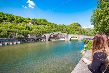 Blond girl contemplates the Bridge of the Devil (Ponte della Maddalena), Lucca.