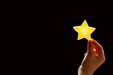 A woman gives a star. The concept of a positive rating, reviews and feedback on black background.