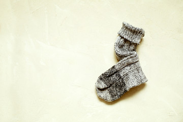 Fototapeta na wymiar Handmade warm knitted sock grey color on textured background with copy space.Winter and autumn concept of eco clothes.Minimalism Kinfolk Style.Horizontal orientation