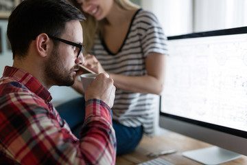 Young couple of designers working on computer