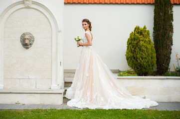 Fototapeta premium Beautiful bride in long wedding dress with bouquet