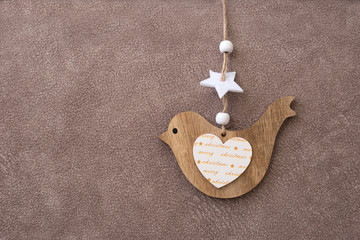 Wooden toy for the Christmas tree in the shape of a bird on a brown background. The symbol of Christmas. Christmas decor. Place for text