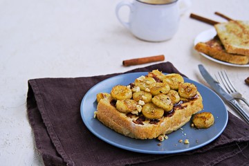 Breakfast, french toasts with banana, walnuts and honey on a gray plate on a light concrete background. French cuisine