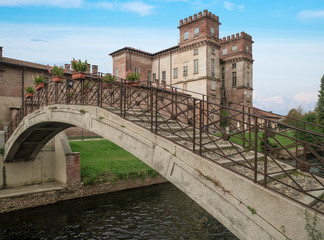 arched bridge in stone and iron and in the background the suggestive restored castle, used as a library.Robecco sul Naviglio, Italy