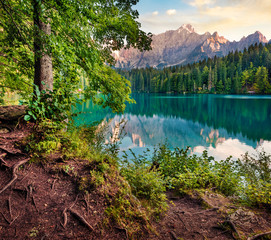 Sunny morning view of Fusine lake. Colorful summer sunrise in Julian Alps with Mangart peak on...