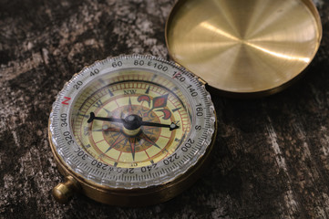 Golden vintage compass on wooden background with natural light