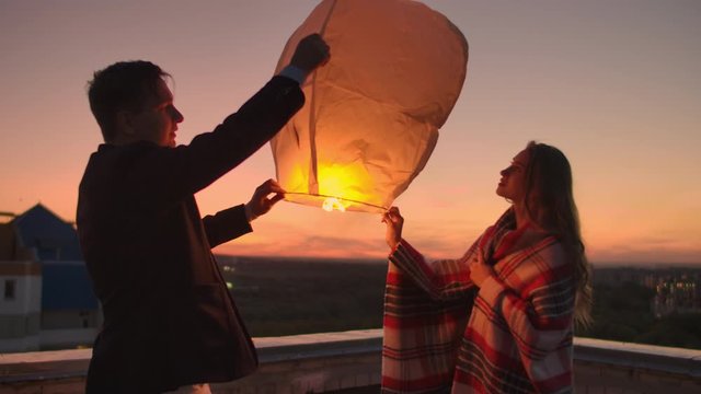 To launch a sky lantern at night on the roof. The lovers are together. Chinese sky lanterns