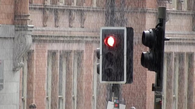 Red British stop traffic light during rainy day English weather.