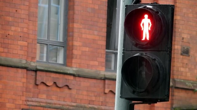 British pedestrian cross walk don't walk stop sign on rainy day traffic scene.