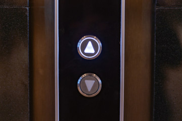 elevator call buttons on a brown wooden panel