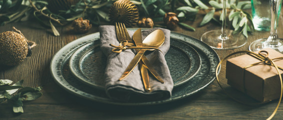 Christmas or New Years celebration party table setting. Plates, golden cutlery, glasses, gift box,...