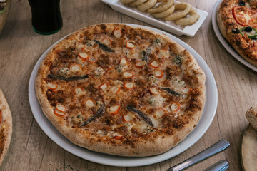 Delicious seafood pizza on white plate on wooden background