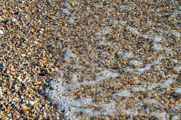 sea pebbles colored granite on the beach background stones. The shore of the beach with sand and pebbles washed by the waves of the sea.