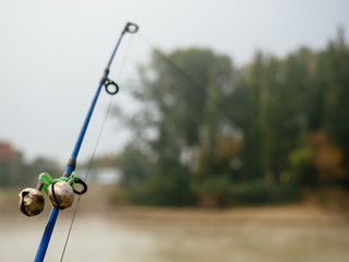 Fishing rod with bells to alert about the bite. Fishing rod in the fog on the river