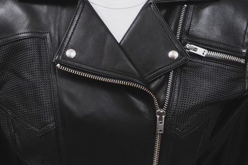 Black leather jacket with perforated elements. Metal zippers, clasps and buttons. Classic clothes for biker. Detailed closeup view. White t-shirt.