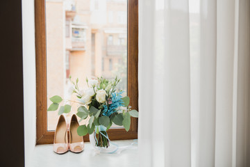 Beautiful modern bridal bouquet of colorful fresh flowers with sikl ribbons. Classic wedding traditional accessory. Leather female shoes standing near it.