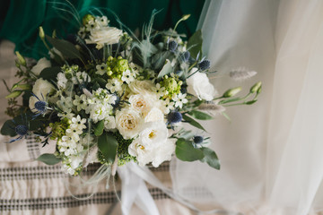 Beautiful modern bridal bouquet of colorful fresh flowers with sikl ribbons. Classic wedding traditional accessory.
