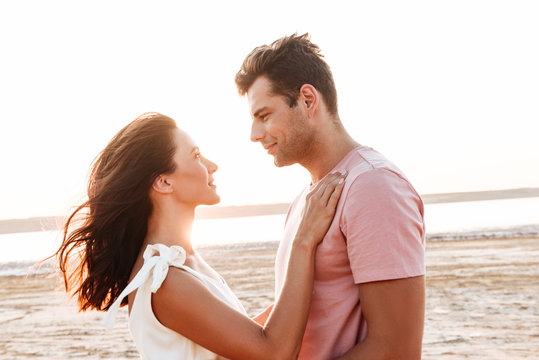 Beautiful young couple wearing summer clothing standing at the beach