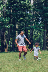 Obraz premium happy african american father and son playing football in park
