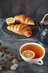 Lemon tea, two fresh croissants and teapot