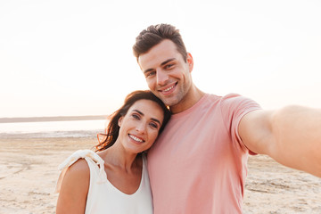 Fototapeta premium Beautiful young couple wearing summer clothing standing at the beach