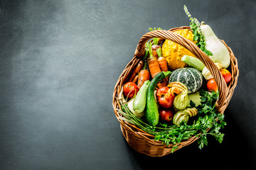 Colorful organic vegetables in wicker basket on black
