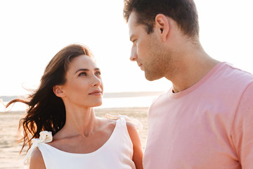 Fototapeta premium Beautiful young couple wearing summer clothing standing at the beach