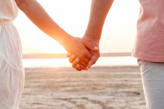 Close up of a couple holding hands at the beach