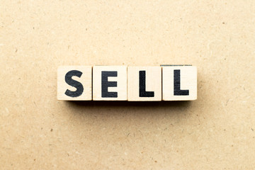 Letter block in word sell on wood background