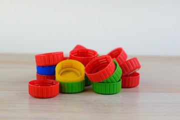 Multicolored plastic caps on wooden background