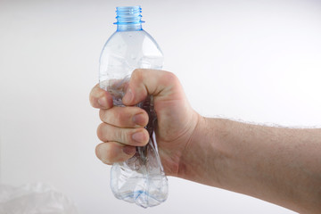 crumpled plastic bottle in hand on white background