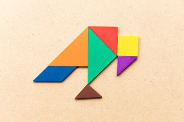 Color tangram puzzle in vulture bird shape on wood background