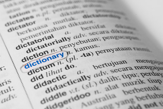 close up of a marked or highlited DICTIONARY word in english to malay dictionary. translator and language concept. Black and white monochrome image with selective colour and soft focus