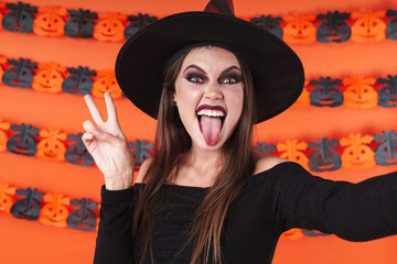 Image of witch girl in halloween costume showing peace sign at camera