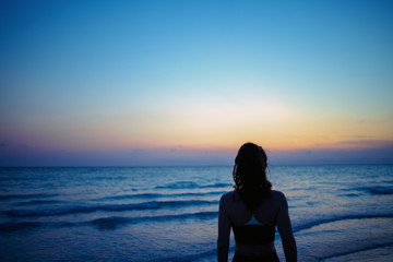 active sports woman on ocean shore in evening relaxing