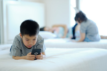 asian chinese boy playing smartphone on bed, kid use phone and play game, addicted game and...