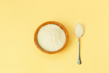 Collagen protein in the bowl and spoon - Hydrolyzed on yellow background