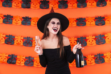 Image of witch girl in black halloween costume holding champagne