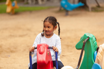 An Asian girl plays a slider on the playing field, creating development