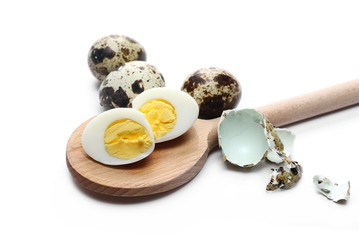 Boiled quail eggs and wooden spoon isolated on white background