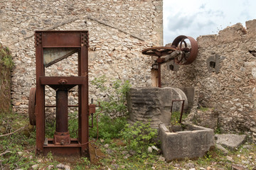 Fototapeta na wymiar rustd olive presses in ruined olive oil factory in abandoned village Palia Plagia, Greece